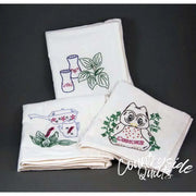 Set of embroidered white kitchen towels featuring floral and kitchenware designs from Aunt Martha’s