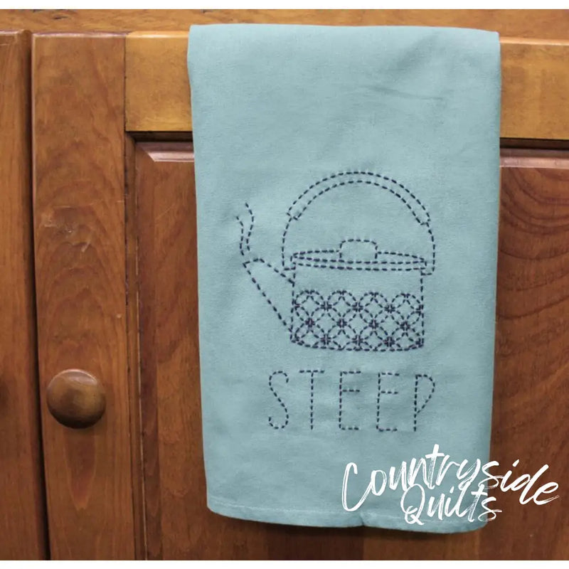 Light blue tea towel with a dotted teapot and STEEP, featuring Aunt Martha’s Sashiko Japanese embroidery