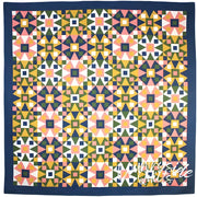 Geometric quilt with star motifs in pink, green, navy from Art East Quilting Co Propeller Quilt Pattern