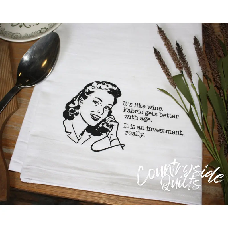 White tea towel with retro illustration reading It’s like wine for Aunt Martha’s Dirty Laundry