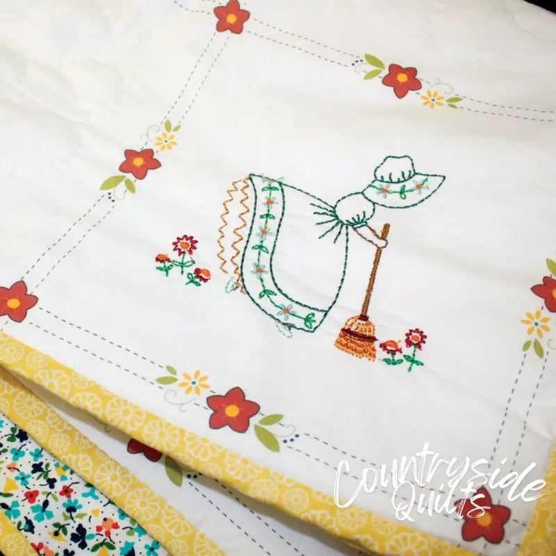 Embroidered tea towel with sunbonnet and broom, featuring Aunt Martha’s quilting retro flower print